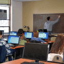 An MSU instructor writes on the board as students work on computers during class in a campus computer lab.